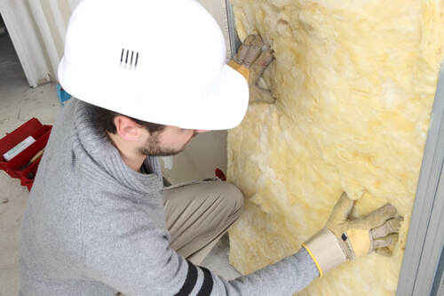 A picture of a person working on a wall insulation service