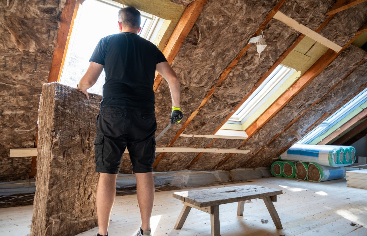 A picture of a man working on an attic insulation material