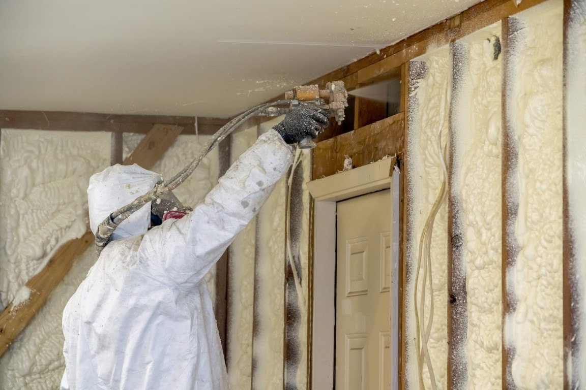 A person applying spray foam insulation in the ceiling