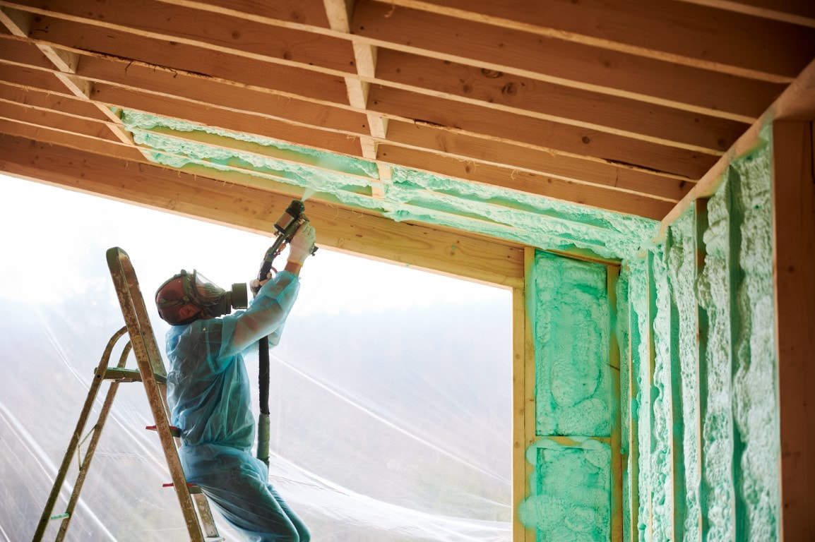 A person applying spray foam insulation in the roof