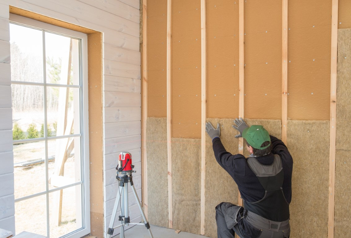 A picture of a person working on a wall insulation