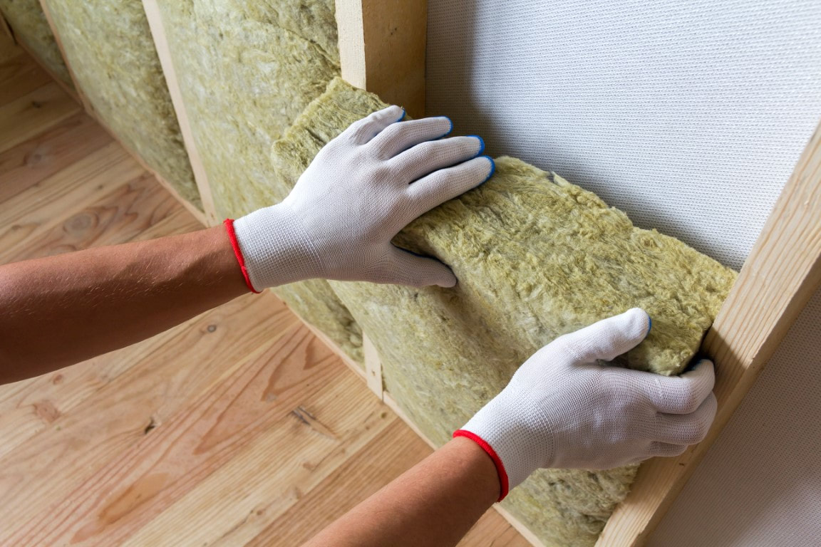A picture of a person working on a wall insulation