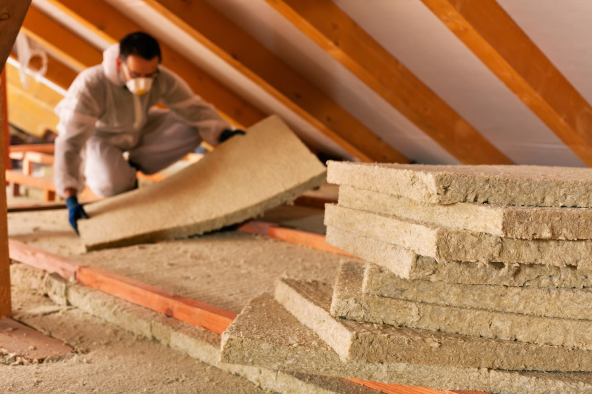 A picture of a man working on an attic insulation material